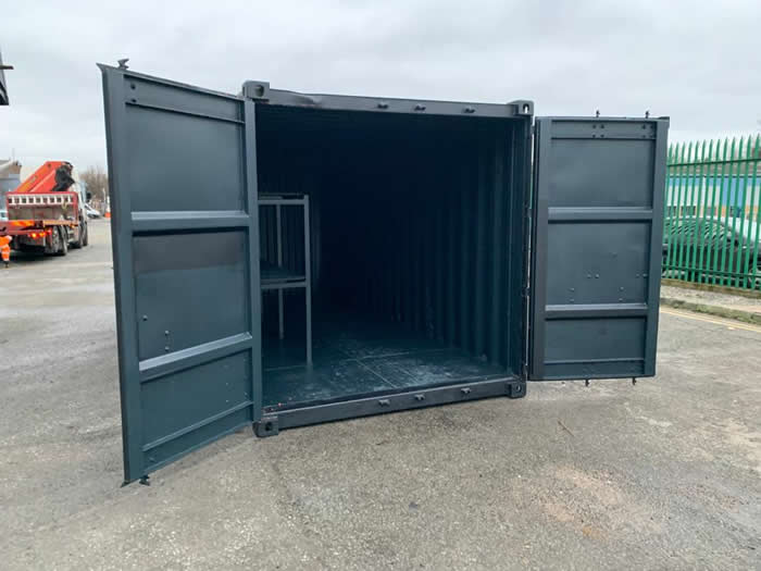 used storage shipping container painted in green open doors